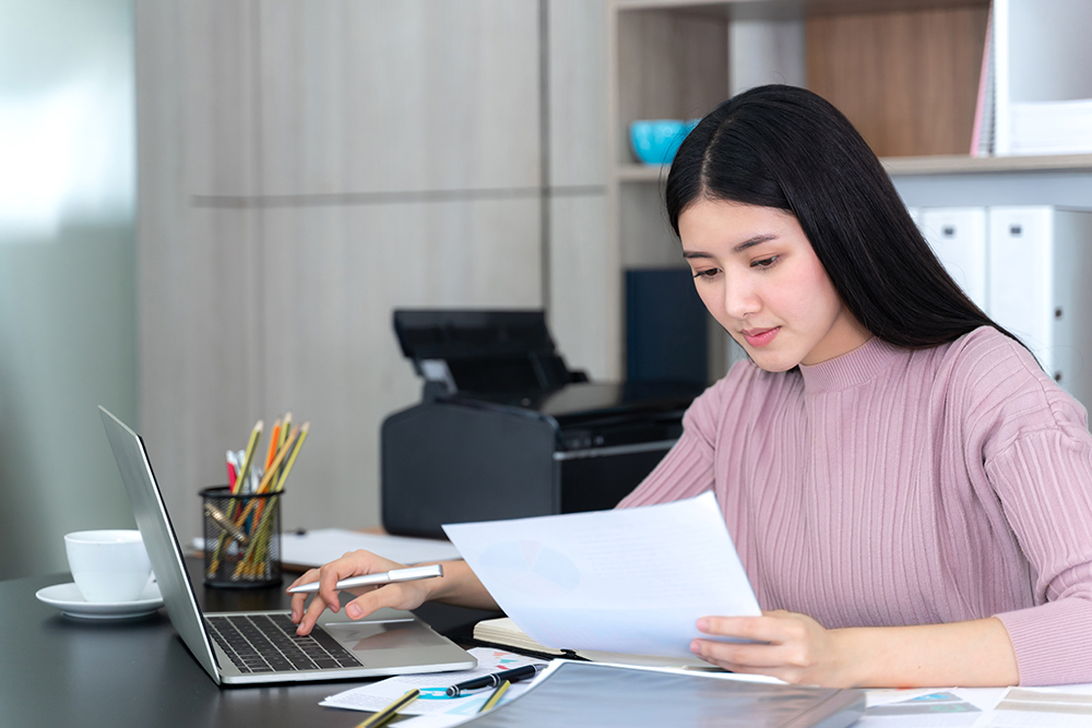 Nữ nhân viên kế toán áo Hồng đang tính toán sổ sách báo cáo thuế